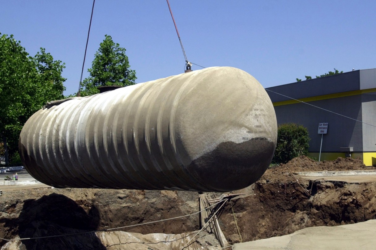FILE - Workers remove a 10,000-gallon underground gasoline storage tank to be replaced with a new tank at a gas station in Sacramento, Calif., May 23, 2003. Nearly half of Americans depend on groundwater for their drinking water, according to the Environmental Protection Agency. Environmental experts say even a pinprick-size hole in an underground tank can send 400 gallons of fuel a year into the ground, polluting soil and water. (AP Photo/Rich Pedroncelli, File)