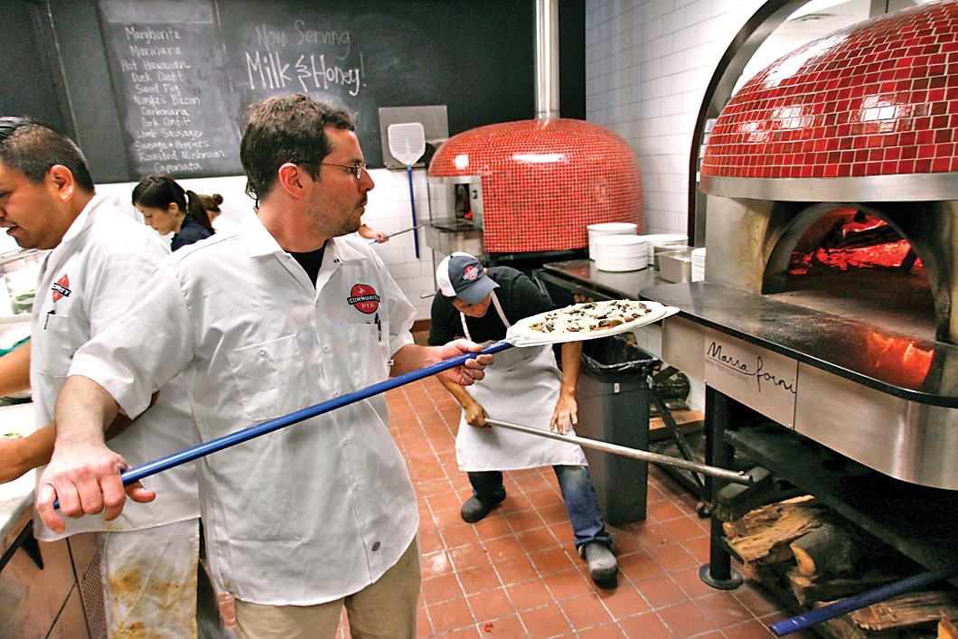 Mike Monen, center, co-owner of Community Pie, works to get orders out during the lunch-hour rush.