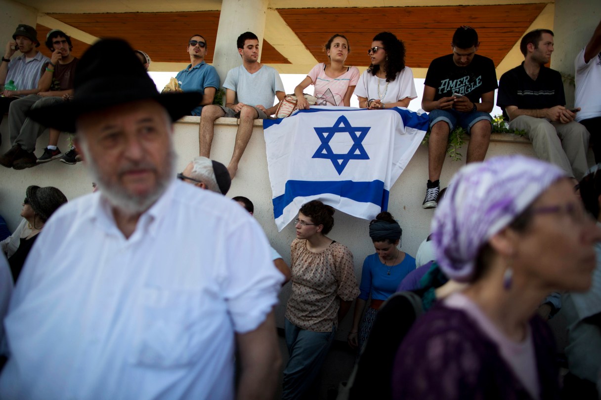 Israelis attend the funeral of three Israeli teenagers, Eyal Yifrah, 19, Gilad Shaar, 16, and Naftali Fraenkel, a 16-year-old with dual Israeli-American citizenship, in the Israeli town of Modiin on Tuesday, July 1, 2014. Tens of thousands of mourners converged Tuesday in central Israel for a funeral service for three teenagers found dead in the West Bank after a two week search and crackdown on the Hamas militant group, which Israeli leaders have accused of abducting and killing the young men.(AP Photo/Oded Balilty)