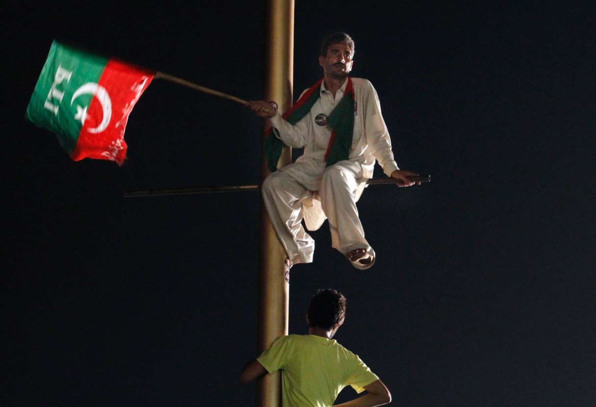 A supporter of Pakistan's cricketer-turned-politician Imran Khan climbs on a pole and listens to his leader's speech during a protest in Islamabad's high-security "Red Zone," in Islamabad, Pakistan, Wednesday, Aug. 20, 2014. Pakistan’s powerful army chief Gen. Rasheel Sharif asked the government to hold negotiations with protesters to settle a mass demonstration outside parliament, officials said. (AP Photo/Anjum Naveed)