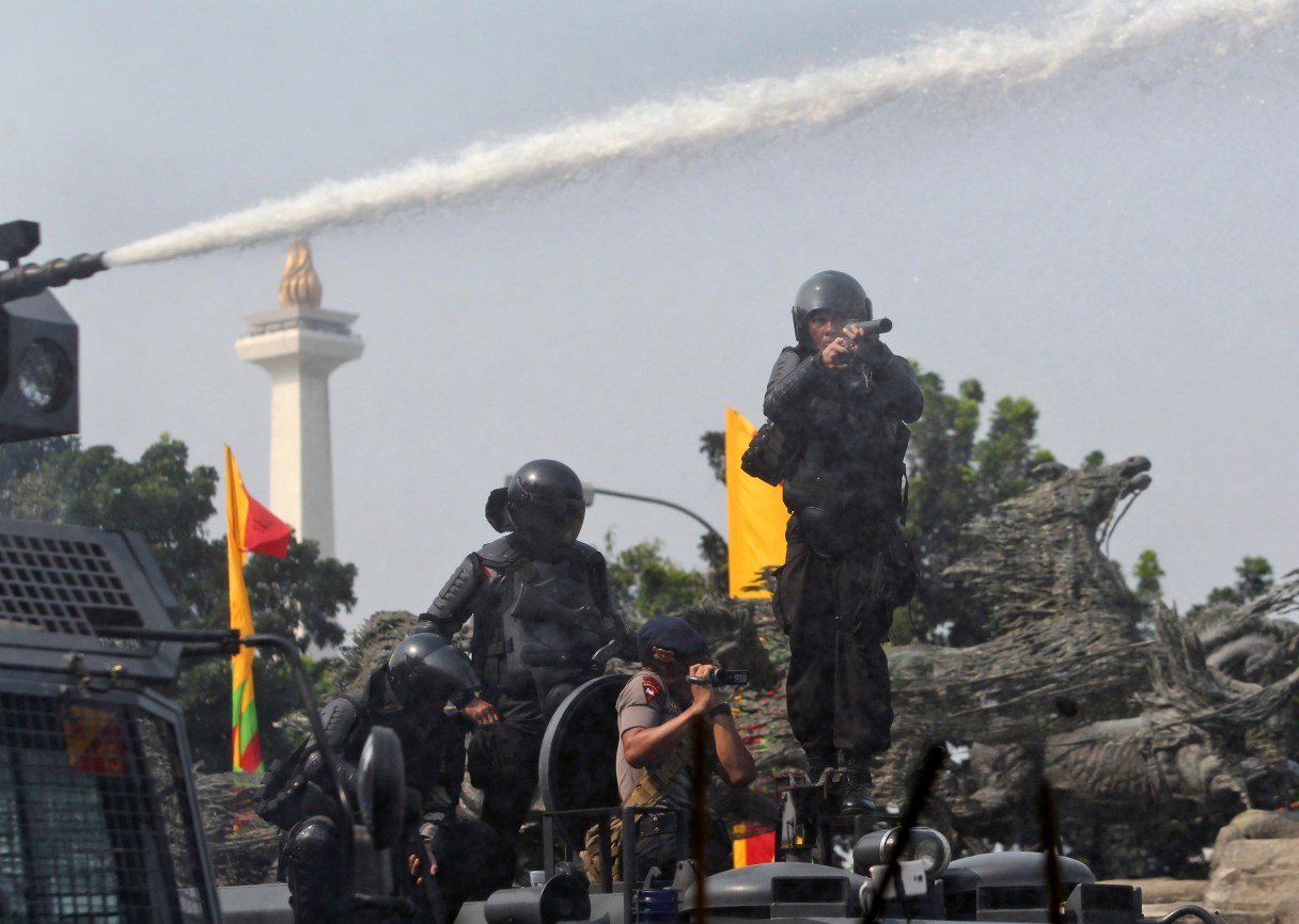 A riot police officer prepares to fire his tear gas launcher during a clash with supporters of losing presidential candidate Prabowo Subianto near the Constitutional Court in Jakarta, Indonesia, Thursday, Aug. 21, 2014. Indonesian police fired tear gas Thursday to disperse protesters trying to get close to the court set to rule on a challenge to the legality of last month's elections. (AP Photo/Tatan Syuflana)