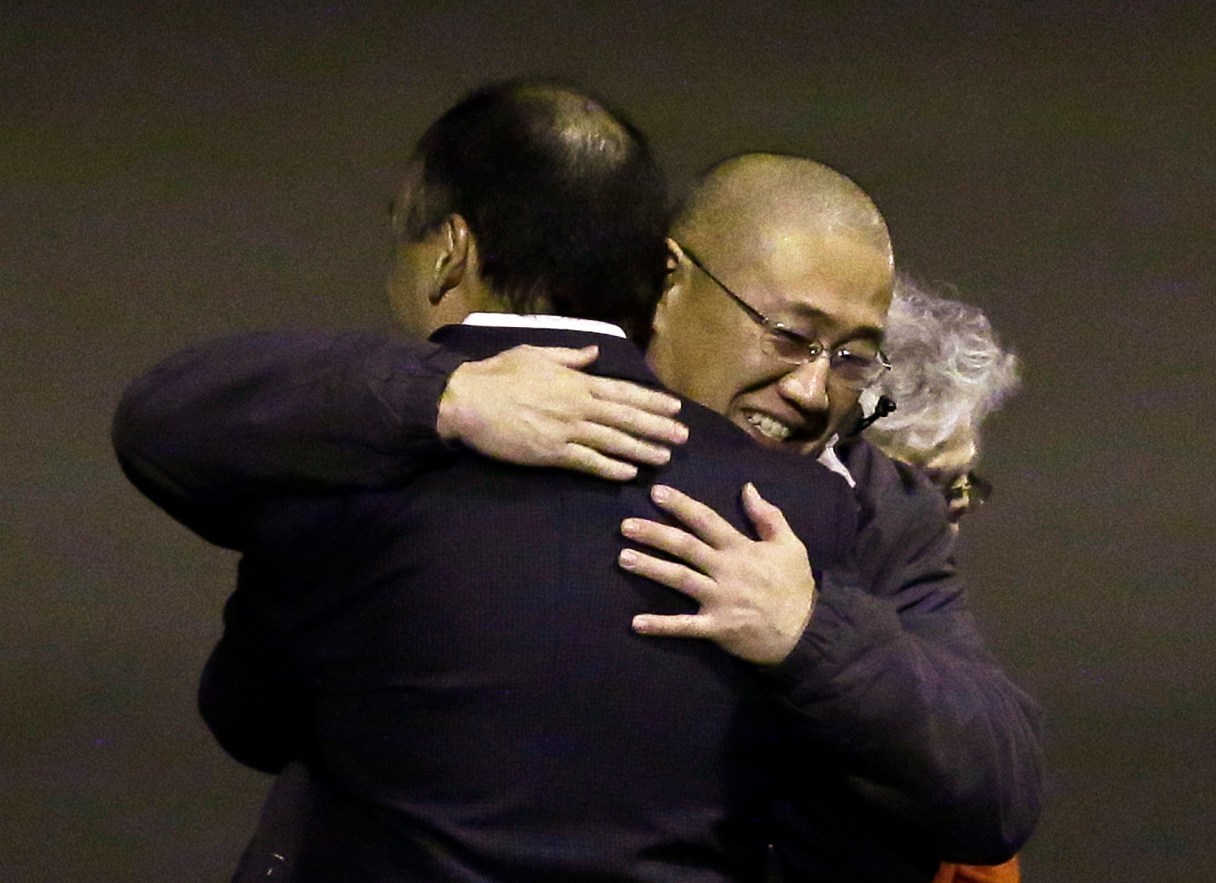 Kenneth Bae, center, who had been held in North Korea since 2012, is hugged after arriving Saturday, Nov. 8, 2014, at Joint Base Lewis-McChord, Wash., after they were freed during a top-secret mission. (AP Photo/Ted S. Warren)