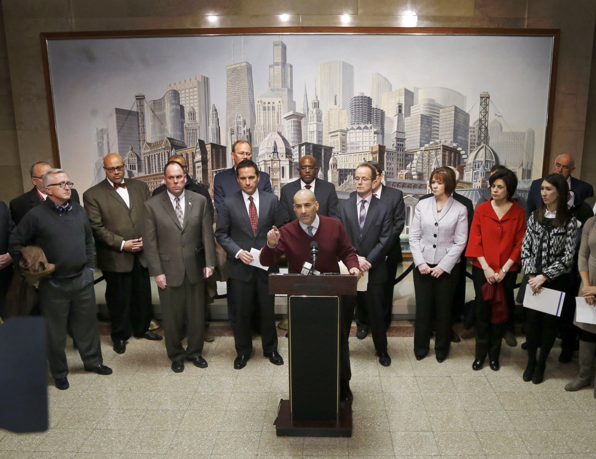 Sam Toia, center, president of the Illinois Restaurant Association, leads Aldermen, merchants, and business leaders in a news conference voicing opposition to a proposed increase of Chicago's minimum wage to $13 an hour Monday, Dec. 1, 2014, in Chicago. Chicago is set to become the latest U.S. city to raise its minimum wage, as Mayor Rahm Emanuel fast-tracks a politically popular plan to reach $13 per hour amid his bid for a second term and criticism that he's out-of-touch with working people. (AP Photo/Charles Rex Arbogast)