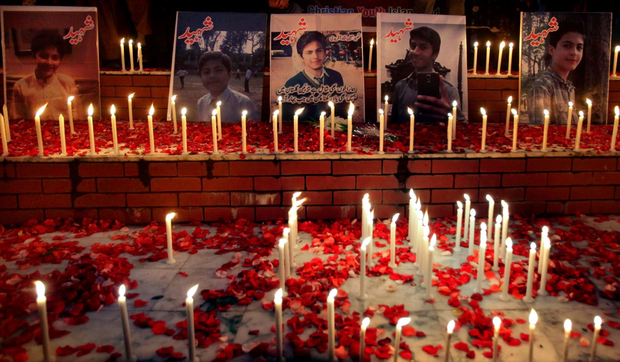 Candles are placed by local residents around portraits of the victims killed in Tuesday's Taliban attack on a military-run school in Peshawar, at a ceremony in Islamabad, Pakistan, Thursday, Dec. 18, 2014. The Taliban massacre that killed more than 140 people, mostly children, at the military-run school in northwestern Pakistan left a scene of heart-wrenching devastation, pools of blood and young lives snuffed out as the nation mourned and mass funerals for the victims got underway. (AP Photo/Anjum Naveed)