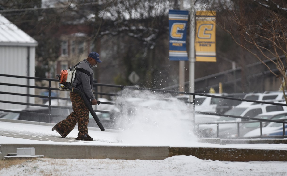 University of Tennessee at Chattanooga employee Arland Jenkins uses a blower to remove snow from the sidewalk leading to the McKenzie Arena on the school's campus Tuesday morning, Feb. 24, 2015, in Chattanooga, Tenn.