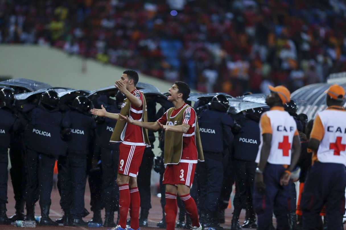 Police shield themselves as Equatorial Guinea's Raul Fabian Bosio, left, and Igor Engonga Noval, appeal to supporters to stop throwing object onto the pitch during their African Cup of Nations Semifinals soccer match with Ghana at Estadio De Malabo, Equatorial Guinea, Thursday Feb. 5, 2015. (AP Photo/Sunday Alamba)