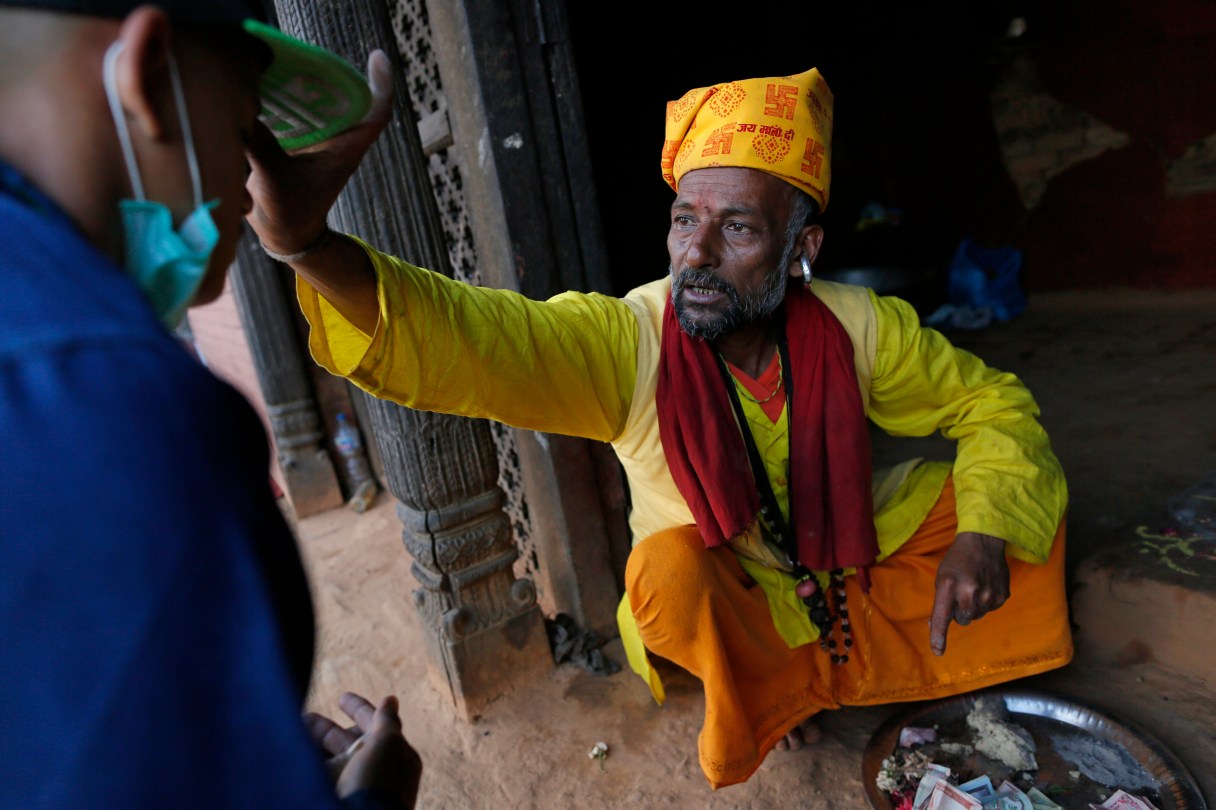 Believing faith in the Hindu gods saved the lives of his village, Hindu priest Ishwar Nath Yogi, 51, blesses followers in the damaged Gorkha Kalika temple in the Pujari village, near the epicenter of last week's massive earthquake, in the Gorkha District of Nepal, Friday, May 1, 2015. (AP Photo/Wally Santana)