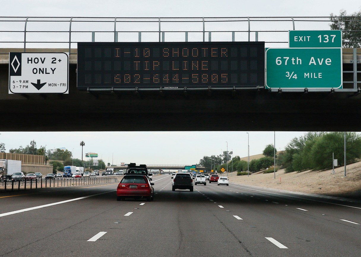 FILE - In this Sept. 10, 2015, file photo, a tip line for motorist hangs on a freeway sign along Interstate 10, in Phoenix. A suspect has been arrested in a string of shootings along Phoenix-area freeways that have kept drivers on edge, state officials said Friday, Sept. 18. (AP Photo/Matt York, File)