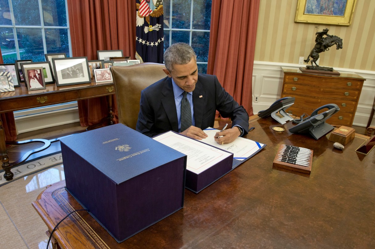 President Barack Obama signs the $1.1 trillion spending bill in the Oval Office at the White House on Friday. (Stephen Crowley/The New York Times)