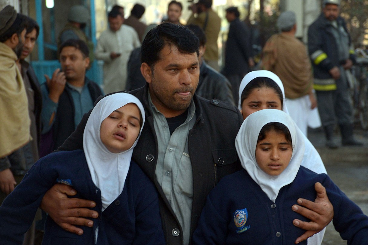 An Afghan man carries two schoolgirls away from a clash site, in Jalalabad, capital of Nangarhar province, Afghanistan, Wednesday, Jan. 13, 2016. Several members of the Afghan security forces were killed Wednesday after unidentified gunmen attacked the Pakistani consulate in a volatile eastern province, an official said on Wednesday. (AP Photos/Mohammad Anwar Danishyar)