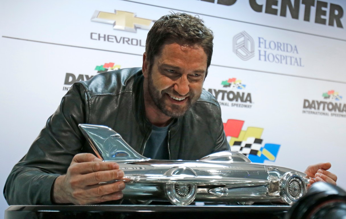 Actor Gerard Butler poses with the Daytona 500 winner's trophy during a news conference before the NASCAR Daytona 500 Sprint Cup Series auto race at Daytona International Speedway in Daytona Beach, Fla., Sunday, Feb. 21, 2016. Butler is the Grand Marshall of the race. (AP Photo/Terry Renna)
