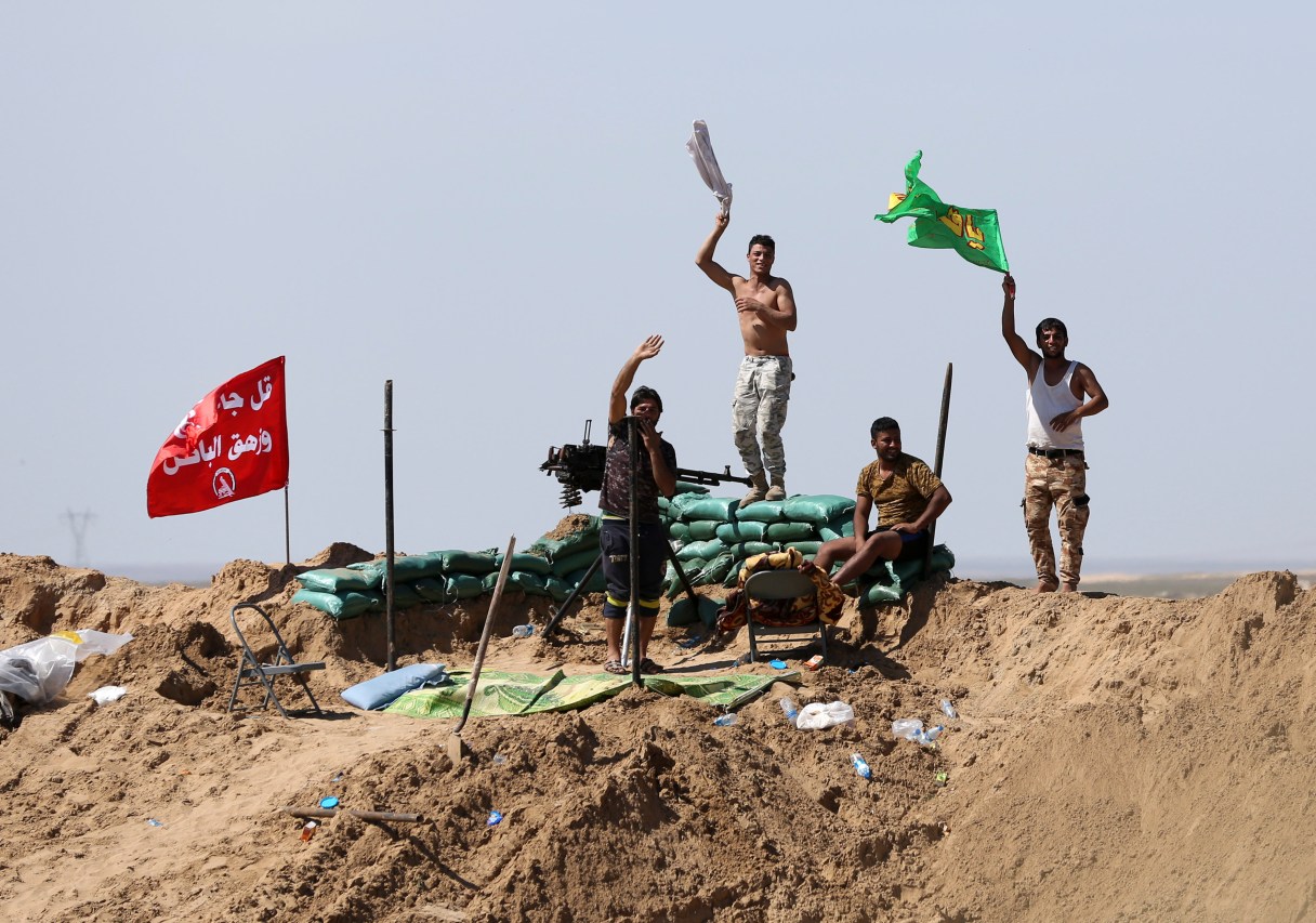FILE - In this Wednesday, March 9, 2016 file photo, Popular Mobilization forces chant slogans against the Islamic State group as Iraqi Defense Minister Khaled al-Obeidi tours the front line in Anbar, Iraq. After months of losing ground in Iraq and Syria, the Islamic State group is showing signs of the wear and tear, with commanders on the ground saying they are seeing an increase in desertions. But the jihadis appear to be lashing back with more terrorist and chemical attacks. (AP Photo/Hadi Mizban, File)