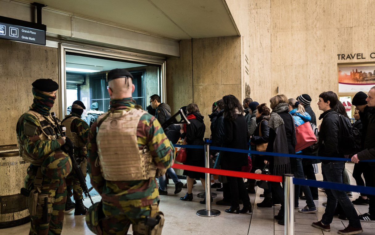 Belgian Army soldiers patrol as passengers line up to have their bags searched at the Central Station in Brussels on Wednesday, March 23, 2016. Belgian authorities were searching Wednesday for a top suspect in the country's deadliest attacks in decades, as the European Union's capital awoke under guard and with limited public transport after 34 were killed in bombings on the Brussels airport and a subway station. (AP Photo/Valentin Bianchi)
