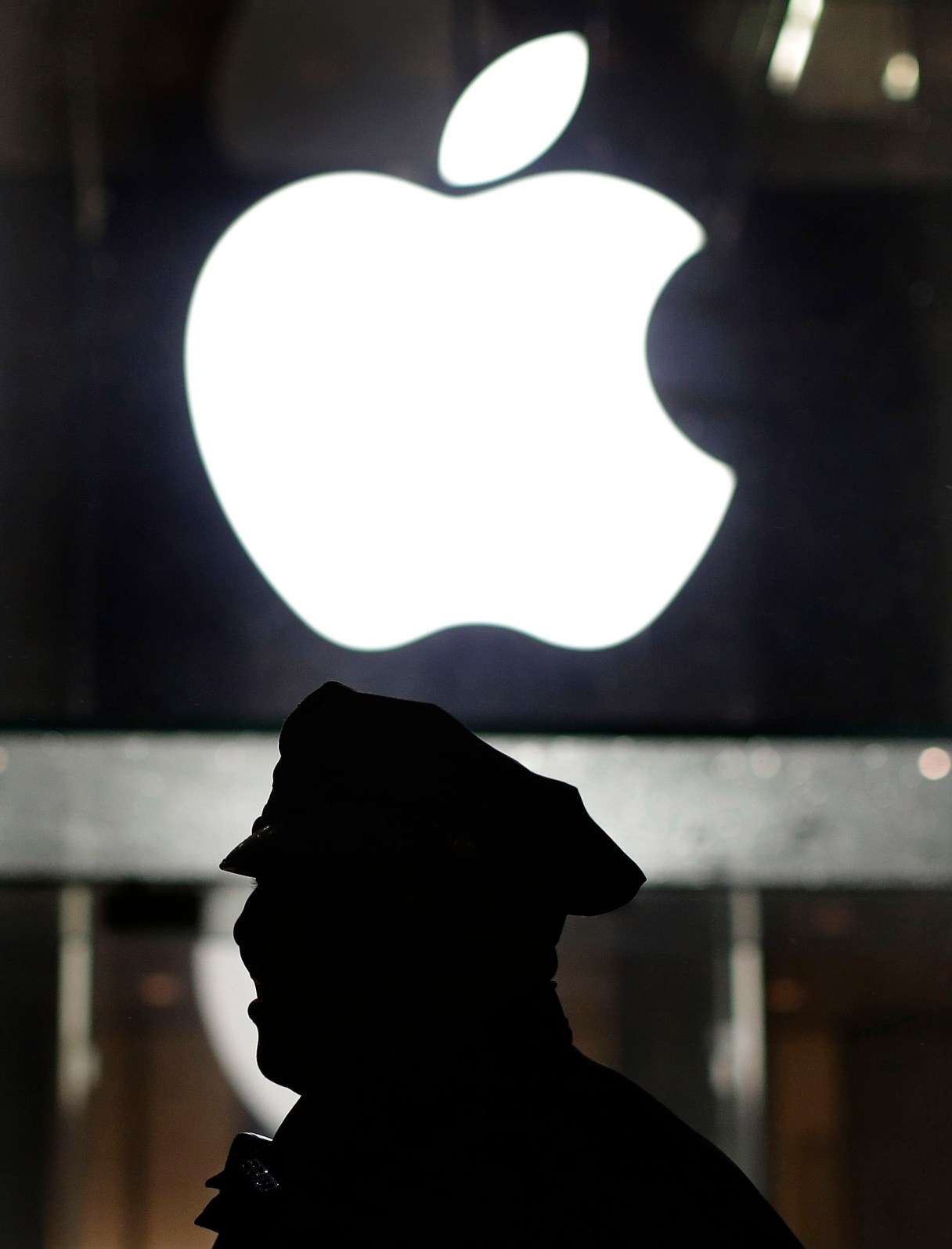 FILE - This Feb. 23, 2016, file photo shows a New York police officer stands outside the Apple Store on Fifth Avenue while monitoring a demonstration, in New York. San Bernadino District Attorney Michael Ramos suggests in a court filing that one of the San Bernardino shooters might have used his iPhone, the same one at the heart of Apple's battle with the FBI, to introduce a "lying-dormant cyber pathogen" into the county's computer network. (AP Photo/Julie Jacobson, File)