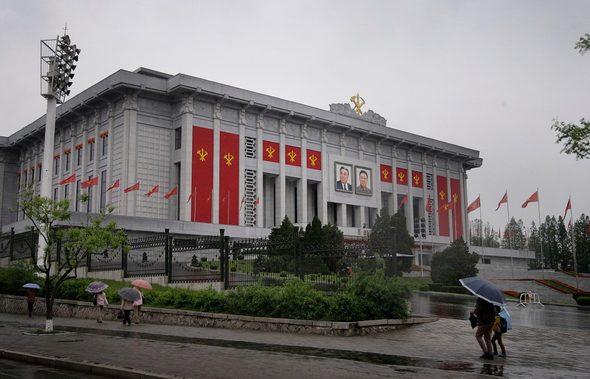 In this Thursday, May 5, 2016, photo, North Koreans walk past the April 25 House of Culture decorated in the colors and flags of their ruling party, Workers' Party, in Pyongyang, North Korea. North Korea’s elite are gathered in Pyongyang ahead of their biggest political conference in decades. Foreign experts say leader Kim Jong Un will likely use the meeting, which starts Friday, to push his expansion of a nuclear arsenal over the strong objections of the U.S., the U.N. and North Korea's neighbors, including ally China. (AP Photo/Wong Maye-E)