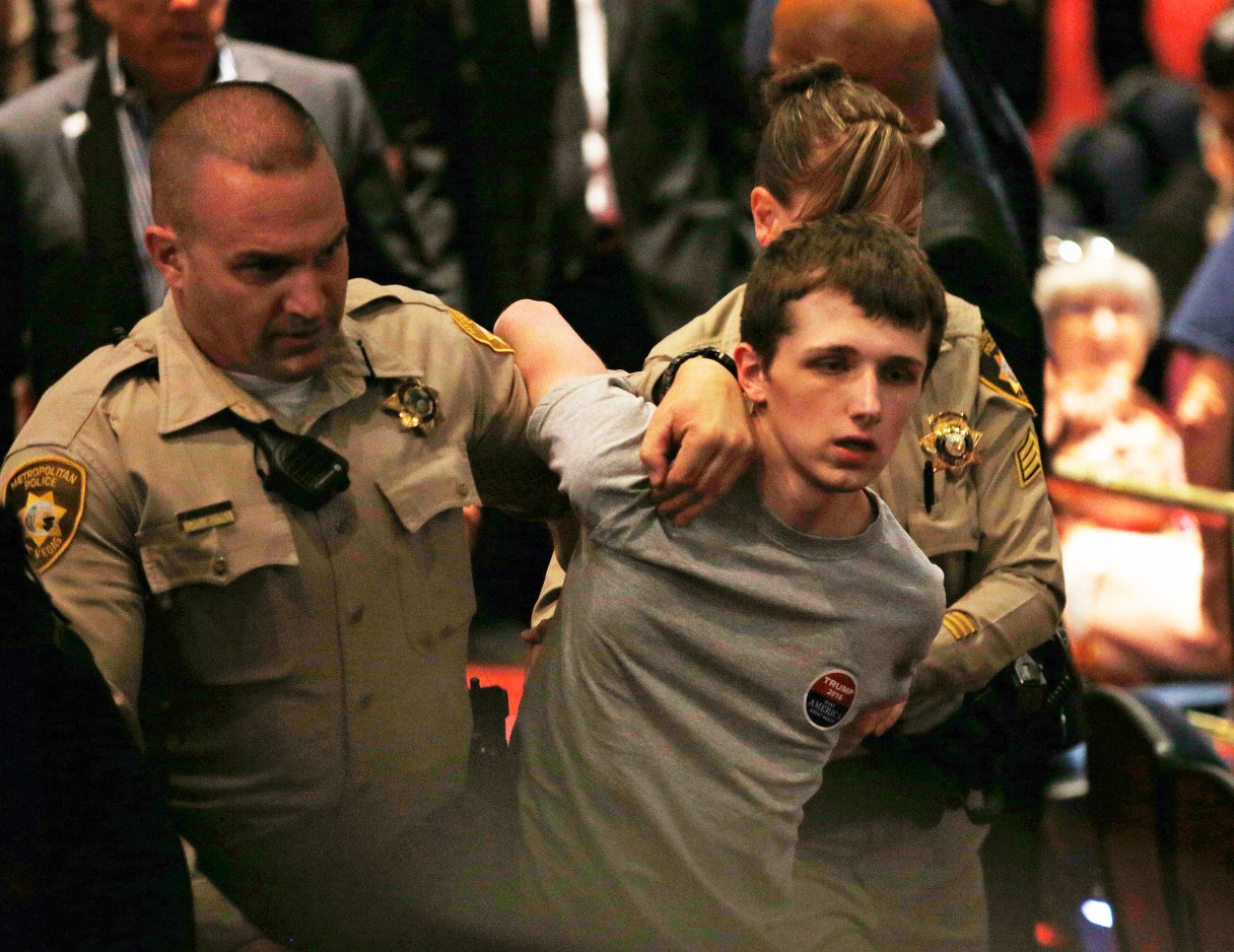 In this June 18, 2016, photo, police remove Michael Steven Sandford as Republican presidential candidate Donald Trump speaks at the Treasure Island hotel and casino in Las Vegas. Sandford, a British man accused of trying to take a police officer's gun and kill Donald Trump during a weekend rally in Las Vegas, will not be released on bail. Federal Magistrate Judge George Foley said at a hearing Monday that Sandford was a potential danger to the community and a flight risk. (AP Photo/John Locher)