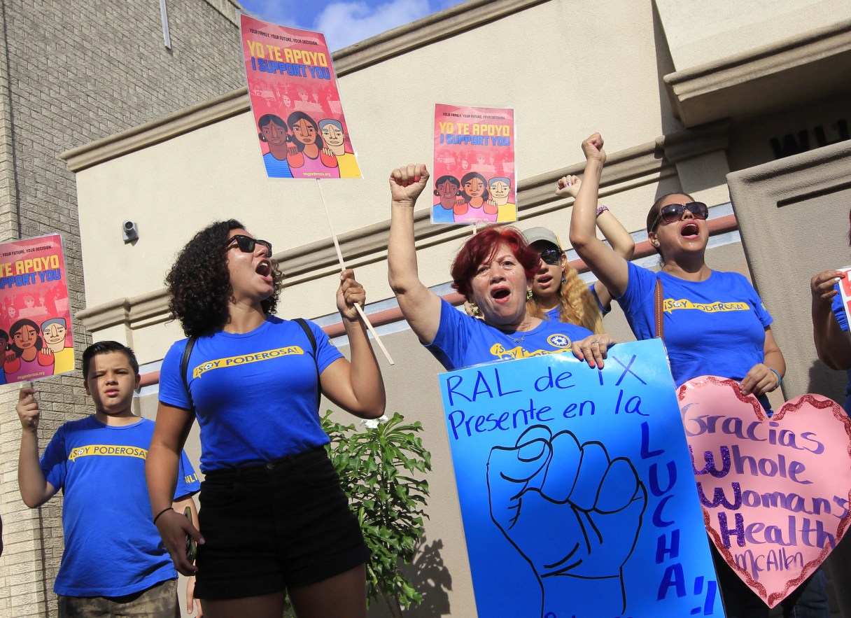 Lucy Ceballos, center, and Isabella Soto, left, members of the National Institute for Reproductive Health, celebrate the U.S. Supreme Court ruling against Texas' abortion restrictions in front of Whole Woman's Health Monday, June 27, 2016, in McAllen, Texas. Whole Woman's Health is a abortion provider that stayed open despite the restrictions as many other providers closed over the past two years. (Nathan Lambrecht/The Monitor via AP)
