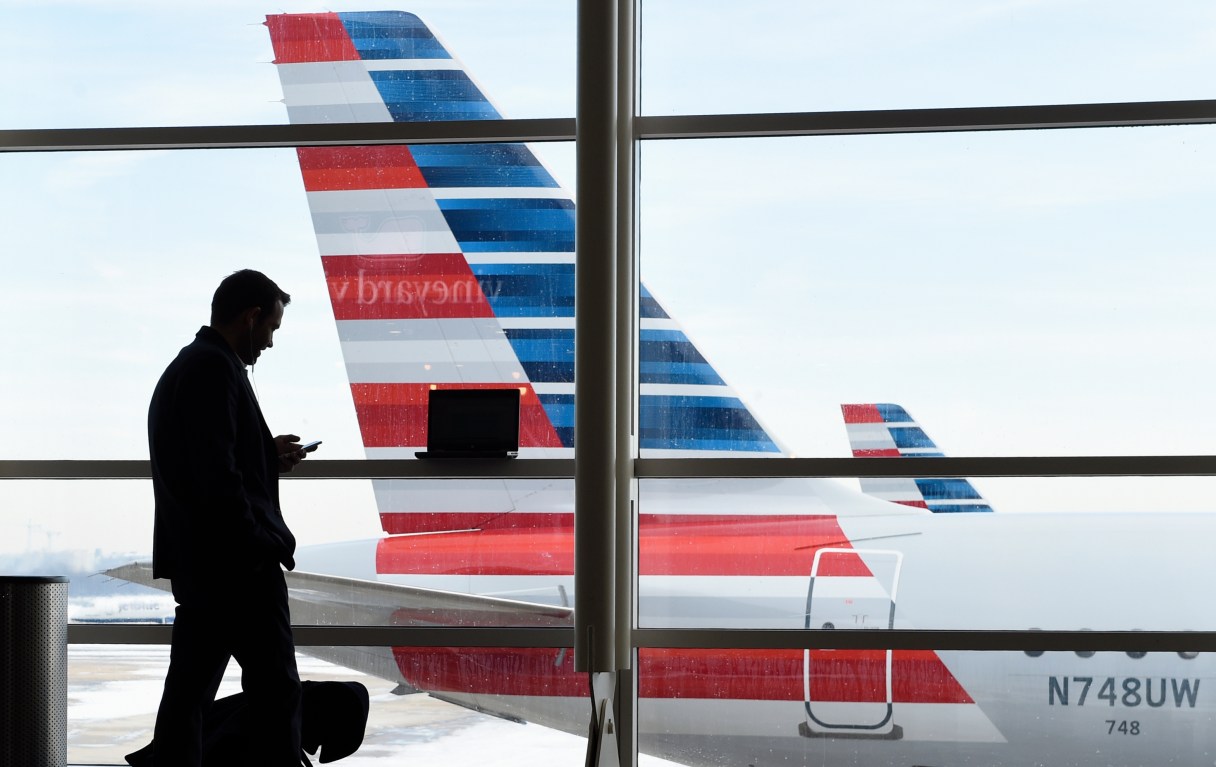 FILE - In this Jan. 25, 2016, file photo, a passenger talks on the phone as American Airlines jets sit parked at their gates at Washington's Ronald Reagan National Airport. American Airlines announced Wednesday, Jan. 18, 2017, that passengers will be able to buy “basic economy” tickets starting in February that will be similar to bare-bones fares already offered by Delta Air Lines and soon to be matched by United Airlines. The basic-economy fares will have a lower price, but will offer fewer comforts. (AP Photo/Susan Walsh, File)