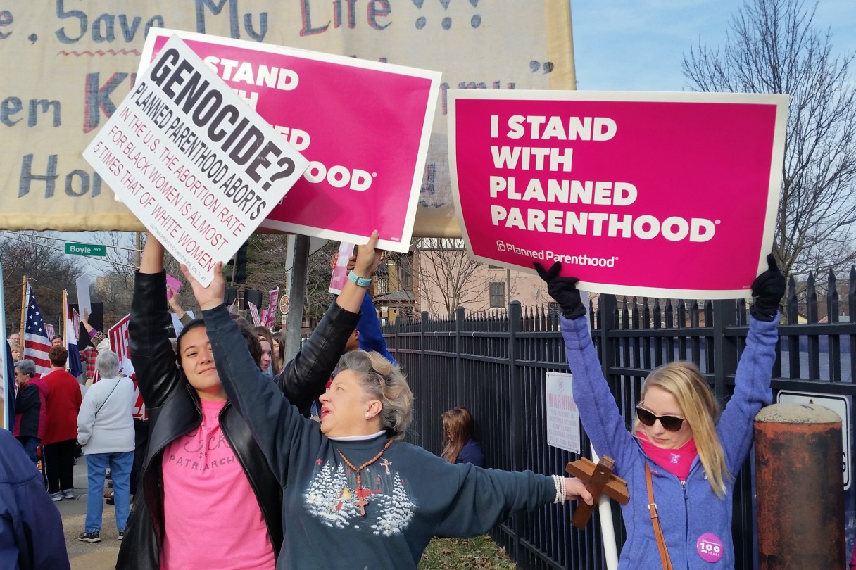 A Planned Parenthood supporter and opponent try to block each other's signs during a protest and counter-protest Saturday, Feb. 11, 2017 in St. Louis. Rallies aimed at urging Congress and President Donald Trump to end federal funding for Planned Parenthood are scheduled across the country. (AP Photo/Jim Salter)