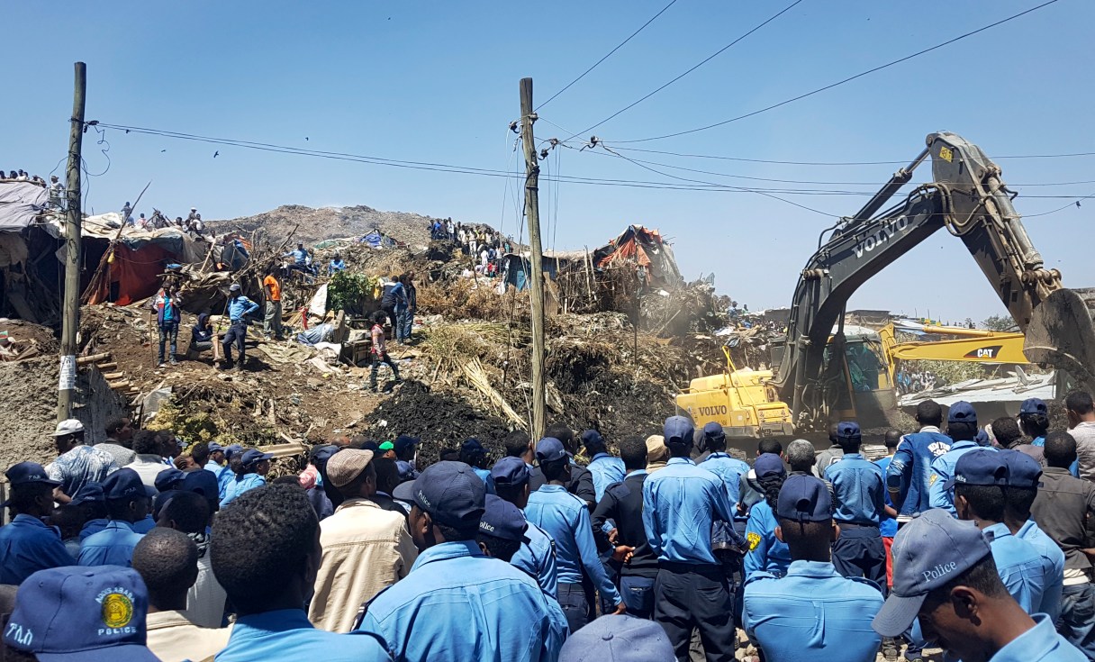 Police officers secure the perimeter at the scene of a garbage landslide, as excavators aid rescue efforts, on the outskirts of the capital Addis Ababa, Ethiopia Sunday, March 12, 2017. Officials and residents say more than a dozen people have been killed in a landslide at a massive garbage dump on the outskirts of Ethiopia's capital, and several dozen people are missing. (AP Photo/Elias Meseret)