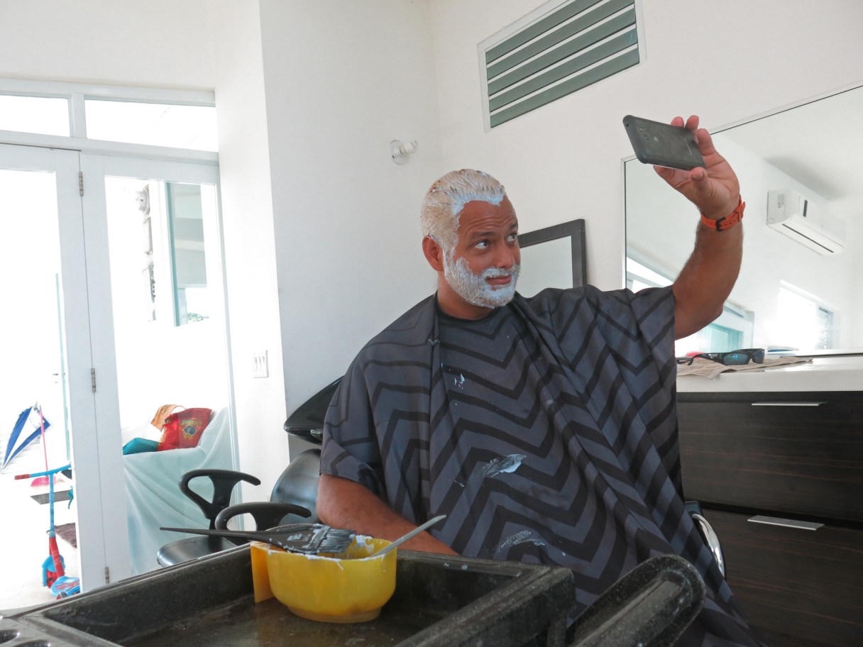 Civil engineer Christian Rodriguez takes a selfie to send to his wife as he gets his hair and beard dyed blonde in support of Puerto Rico's baseball team in San Juan, Puerto Rico, Tuesday, March 21, 2017. Pharmacies and beauty stores across Puerto Rico are running out of hair dye as a growing number of men go blond in support of the island's baseball players who bleached their hair as a bonding ritual ahead of the World Baseball Classic. (AP Photo/Danica Coto)