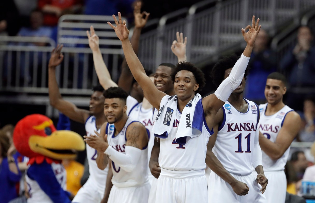 Kansas guard Devonte' Graham, center, celebrates with teammates during the second half of a regional semifinal against Purdue in the NCAA men's college basketball tournament, Thursday, March 23, 2017, in Kansas City, Mo. Kansas won 98-66. (AP Photo/Charlie Riedel)