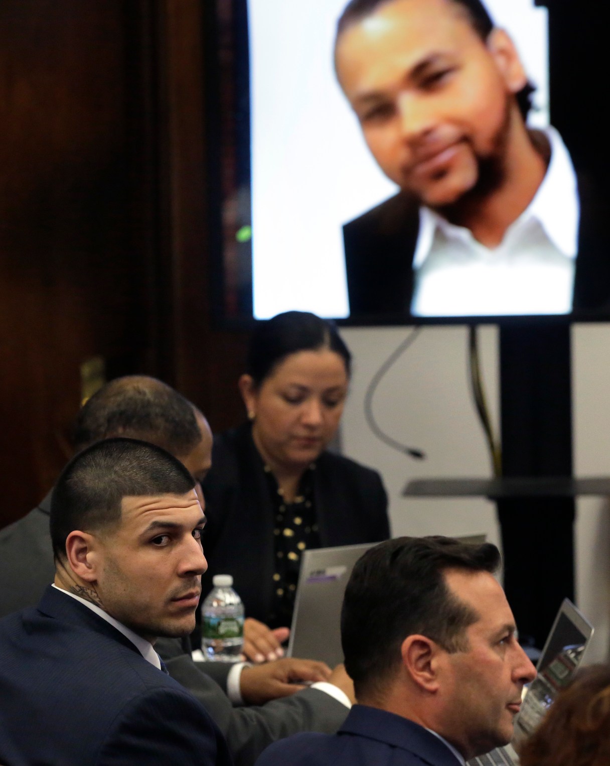 Former New England Patriots tight end Aaron Hernandez, left, sits in court as an image of shooting victim Daniel de Abreu is projected, top right, during his double murder trial at Suffolk Superior Court Wednesday, March 1, 2017, in Boston. Hernandez is charged in the July 2012 killings of Daniel de Abreu and Safiro Furtado who he encountered in a Boston nightclub. The former NFL football player already is serving a life sentence in the 2013 killing of semi-professional football player Odin Lloyd. (AP Photo/Steven Senne, Pool)