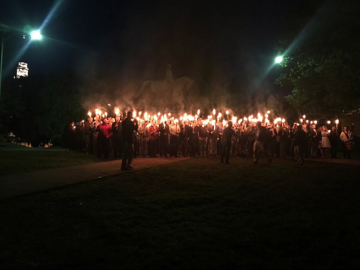 In this Saturday, May 13, 2017, photo, with a Gen. Robert E. Lee statue in the background, people gather at Lee Park in Charlottesville, Va., to protest the plans to remove the monument. (Allison Wrabel/The Daily Progress via AP)