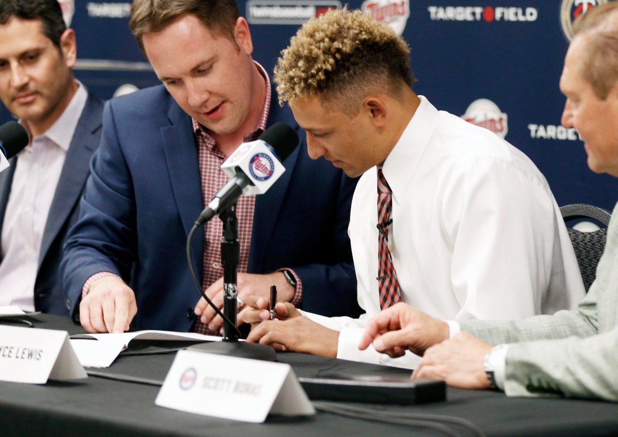 Minnesota Twins chief baseball officer Derek Falvey, second from left, shows first overall MLB draft pick Royce Lewis, right, where to sign his contract as Lewis was introduced to the media between games of a doubleheader against the Cleveland Indians, Saturday, June 17, 2017, in Minneapolis. (AP Photo/Jim Mone)