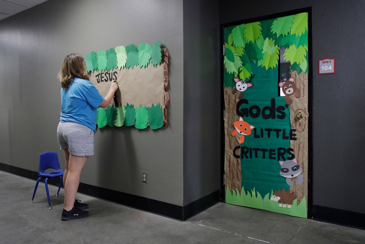 In this photo taken Aug. 8, 2017, Megan Mitchum decorates the outside of a classroom in preparation for the start of the school year at the Mountain View Christian Schools in Las Vegas. More than a third of U.S. states have created school voucher programs that bypass thorny constitutional and political issues by turning them over to non-profits that rely primarily on businesses to fund them. But the programs are raising questions about transparency and accountability at a time when supporters are urging that it be expanded into a federal program. (AP Photo/John Locher)
