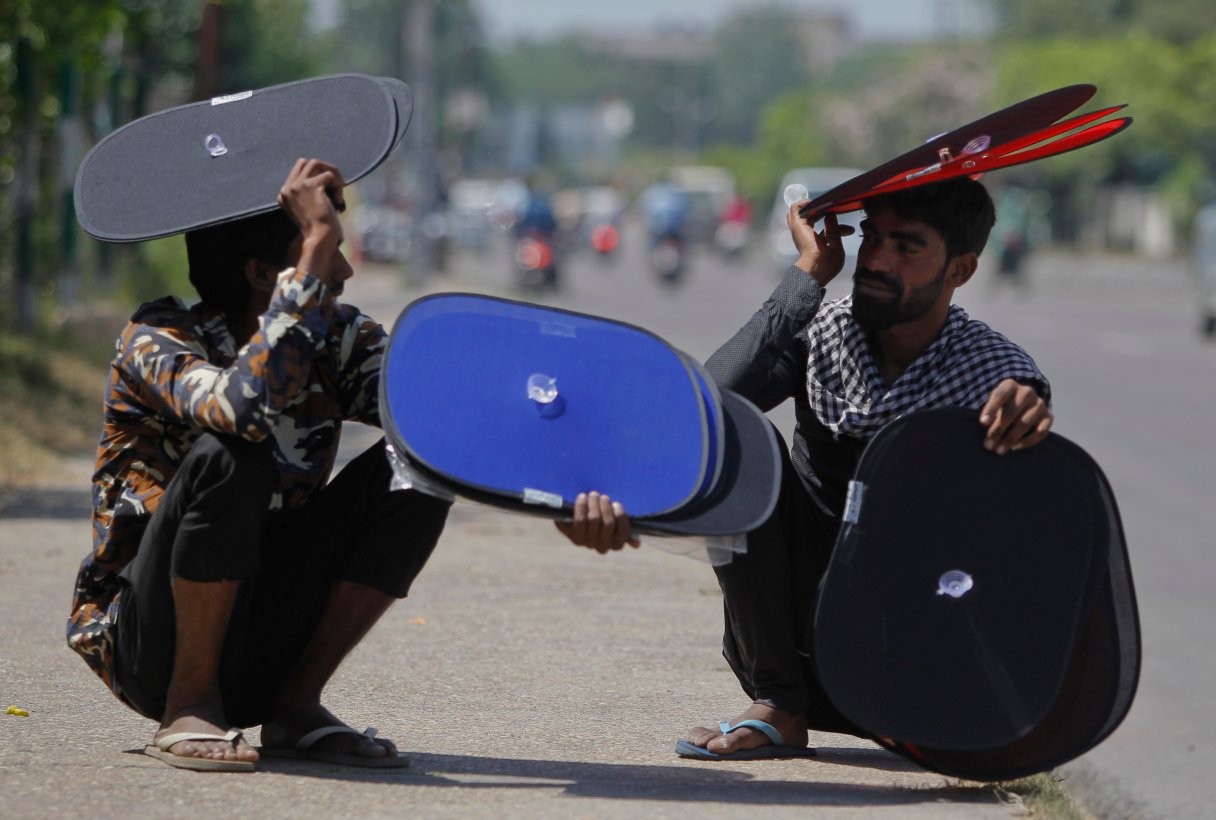 FILE- In this May 17, 2016 file photo, Indian vendors who sell sunshades for car windows take rest by a roadside on a hot summer afternoon in Jammu, India. A new study suggests wide swaths of northern India, southern Pakistan and parts of Bangladesh may become so hot and humid by the end of the century it will be deadly just being outdoors. Such conditions would threaten up to a third of the 1.5 billion people living in those regions, unless the global community can rein in climate-warming carbon emissions. (AP Photo/Channi Anand, File)
