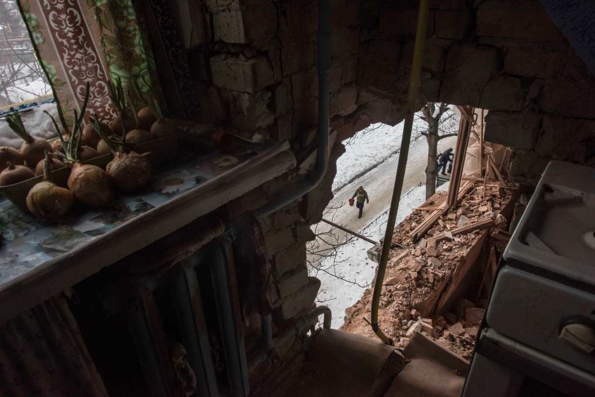 FILE - In this Saturday, Feb. 4, 2017 file photo a local resident walking in a street is seen through a hole in an apartment building damaged by shelling in Avdiivka, Ukraine. Fighting in eastern Ukraine sharply escalated this week. The Ukrainian command said Saturday that several soldiers were killed in the past day. (AP Photo/Evgeniy Maloletka, File)