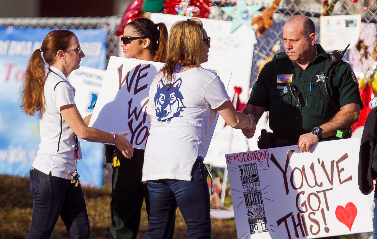 Faculty and staff greet police officers stationed outside of at Marjory Stoneman Douglas High School on Wednesday, Feb. 28, 2018 in Parkland, Fla. With a heavy police presence, classes resumed for the first time since several students and teachers were killed by a former student on Feb. 14. (Matias J. Ocner/Miami Herald via AP)