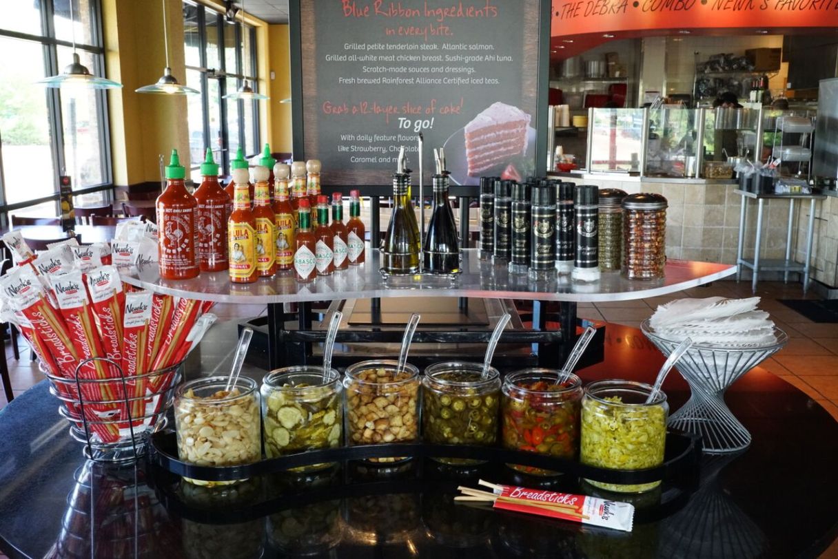 The "Roundtable" feature in the dining room of Newk's Eatery offers premium garnishes such as pickles, oils, cheeses and breadsticks.