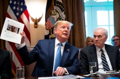 President Donald Trump on Tuesday holds up a photo of Rep. Ilhan Omar, D-Minnesota, during a meeting at the White House, denying that his tweets suggesting she and three other minority congresswomen leave the country were racist. (Doug Mills/The New York Times)