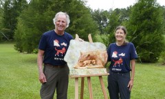 Dale Weiler and Loti Woods pose with a casting of Weiler's red wolf sculpture, "Just Settling In," depicting a mother wolf with her newborn pup. / Photo contributed by Loti Woods