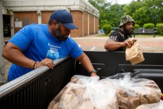 Staff photo by C.B. Schmelter / Troy Rogers, left, and Tony Oliver pass out bagged lunches on the Westside on Tuesday, May 5, 2020 in Chattanooga, Tenn.