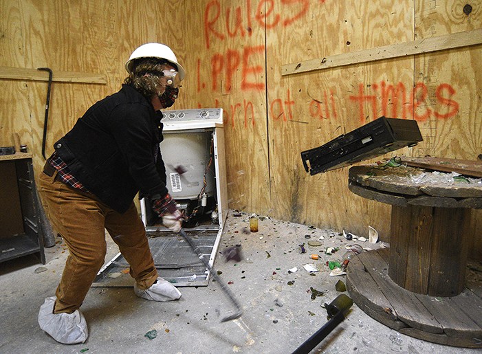 Staff Photo by Matt Hamilton / Writer Jo Kibble smashes a DVD player with a crowbar. Rage rooms are becoming an increasingly popular form of therapy.