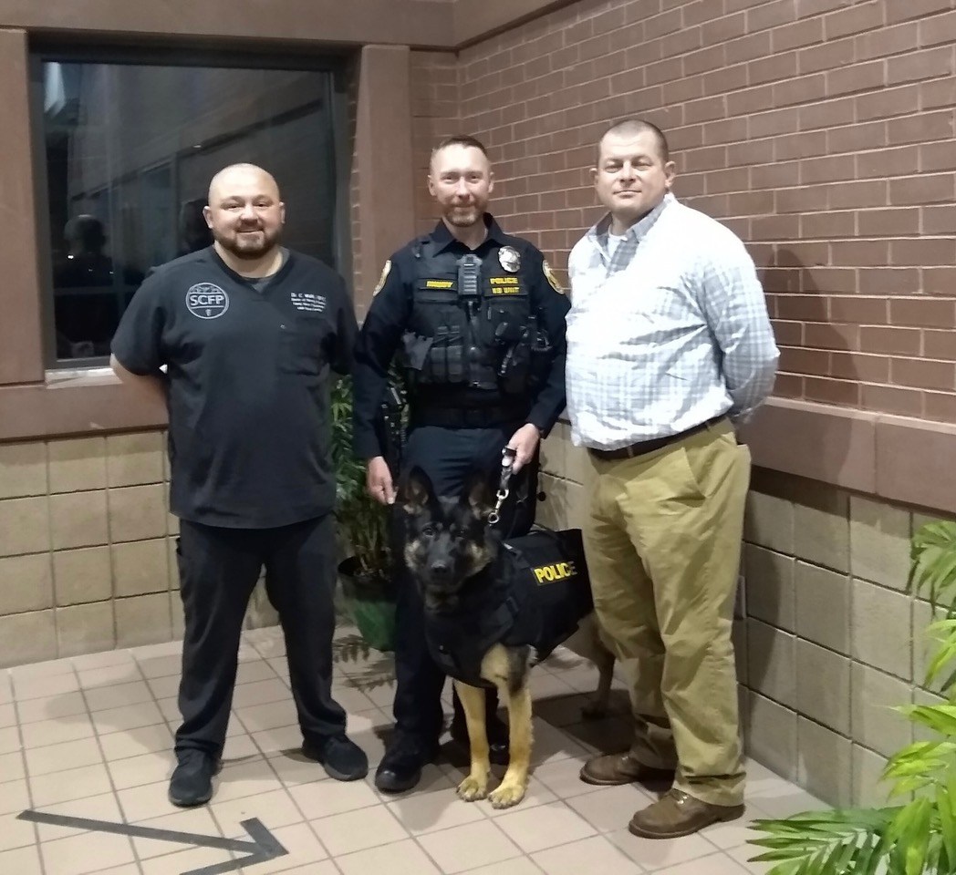 Courtesy photo by Stacy Prater / Dr. Christopher Walls of Scenic City Family Practice poses, from left to right, with East Ridge Police Department K-9 handler Officer Stephen Rhudy, center, K-9 Officer Quest and Stacy Prater of the KC Candle Company.