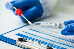 Medical worker holding Coronavirus COVID-19 NP OP swab sample test kit, nasal collection equipment, CDC submitting form, reverse transcription RT-PCR DNA molecular nucleic acid diagnostic procedure covid tile coronavirus tile covid test testing tile / Getty Images