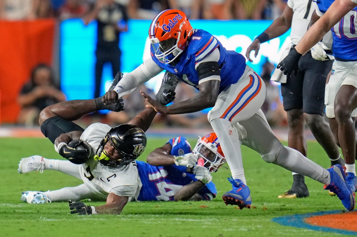 AP photo by John Raoux / UCF running back RJ Harvey, left, dives for extra yardage as he is knocked down by Florida defensive back Jordan Castell, center, and edge rusher Justus Boone last Saturday in Gainesville.