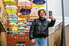 Staff photo by Abby White / Cara Flowers poses to take a selfie in front of Umbrella Alley on Chestnut Street.