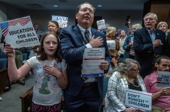 Justin Wilkins of Chattanooga and his daughter, Amy, stand to recite the Pledge of Allegiance as part of a protest of anti-immigrant bills during a meeting of the House Banking and Consumer Affairs Committee on March 19, 2025. (Tennessee Lookout Photo by John Partipilo)
