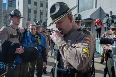 John Partipilo, Tennessee Lookout / Lynne McFarland is held by one state trooper Tuesday while another calls for a police car for her. She was removed from the capitol, where she was opposing a bill to allow exclusion of unauthorized immigrant children from Tennessee schools, one of the bills for which the Hamilton County Republican Party is pushing for yes votes.