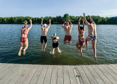 Photo by Kathy Bradshaw / A group of open-water swimmers (with the C.O.W.S.) leap together into the Tennessee River from the North Shore.