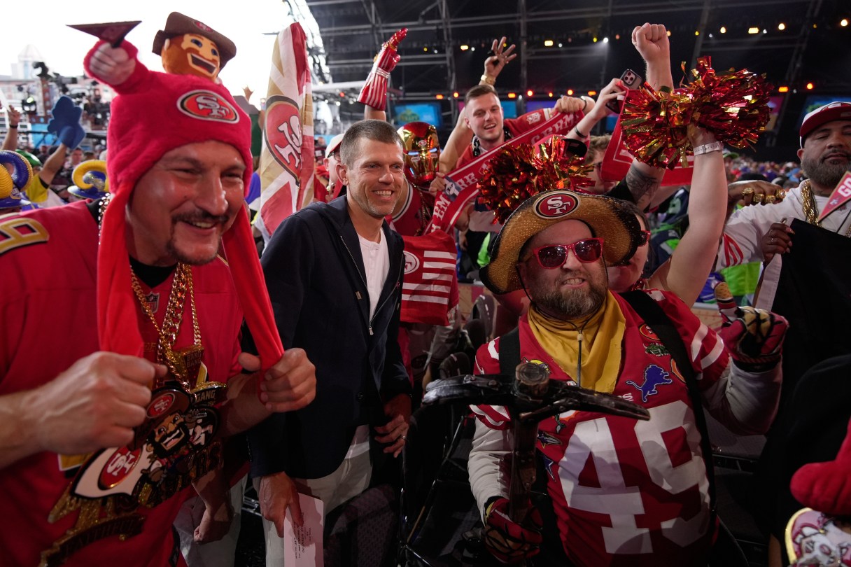 Former NFL player Andy Lee, center, poses with San Francisco 49ers fans during the second round of the NFL draft on April 24 in Pittsburgh. (AP Photo/Sue Ogrocki)