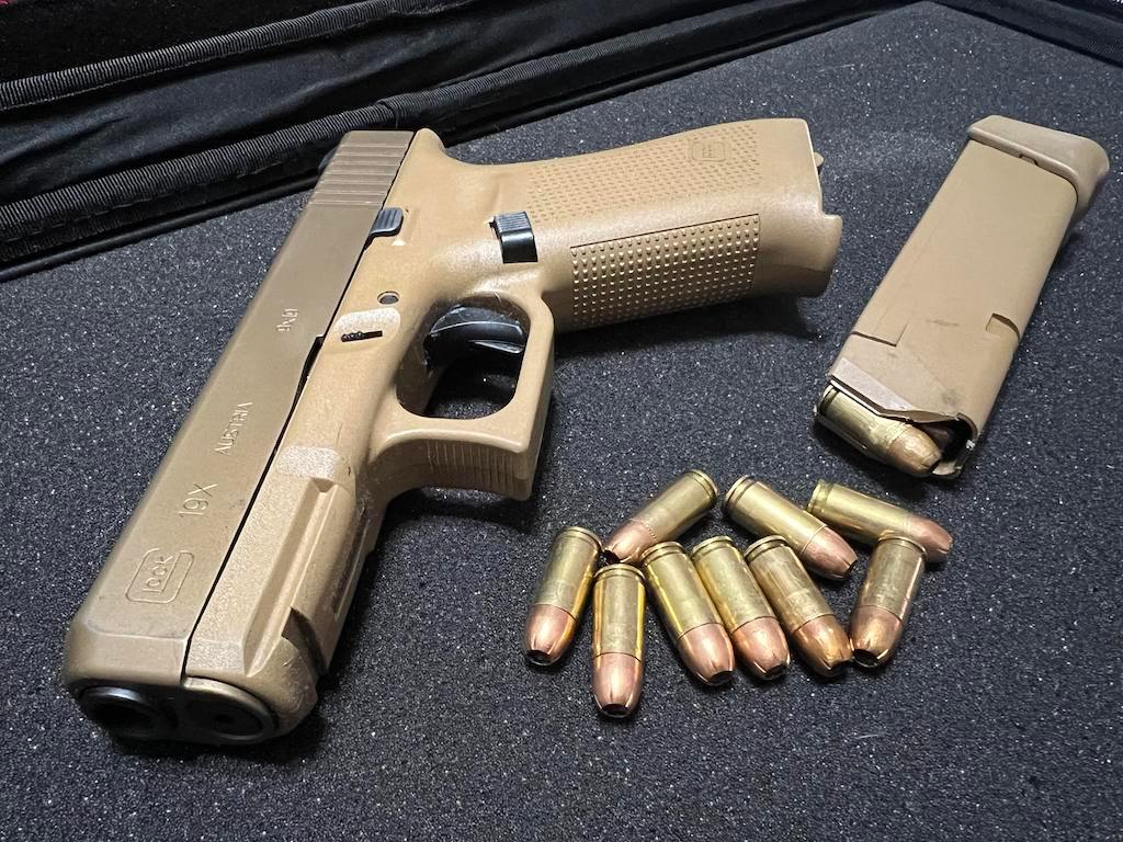 An unloaded Glock 19X handgun sits next to a magazine and 9 mm ammunition at a gun range. Georgia Gov. Brian Kemp recently vetoed a bill that aimed to prevent local governments from punishing motorists for keeping unsecured firearms in cars. (Amanda Watford/Stateline file)
