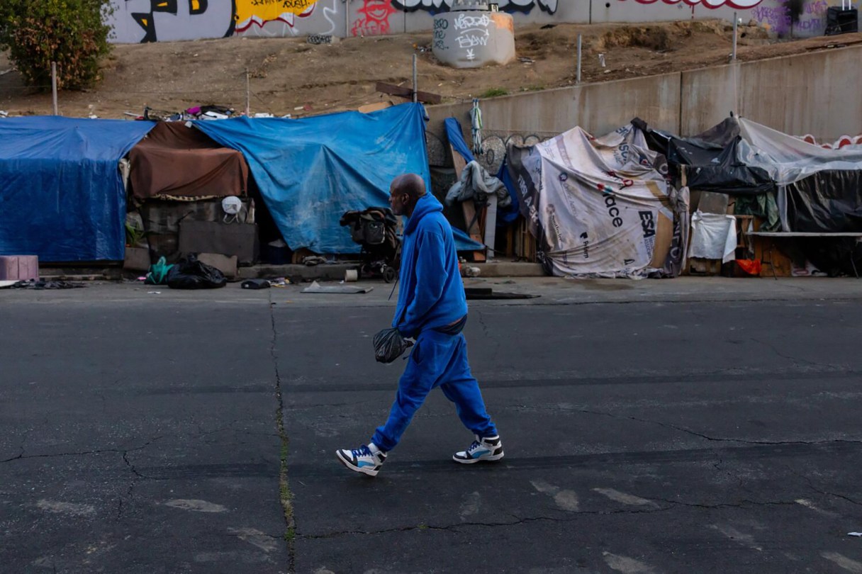 Photo by Jason Armond via Los Angeles Times/TNS / A man walks by a homeless encampment in downtown Los Angeles as a federal judge has found that the city violated the constitutional rights of homeless people in hundreds of cleanups that were not adequately documented to ensure personal property was not seized and destroyed, on Feb. 12, 2026.