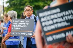 Alabama Reflector Photo by Stew Milne / Auburn University professor Matt Malczycki protests outside the Auburn University Hotel as the university's Board of Trustees meets, Friday, Sept. 11, 2026 in Auburn, Ala. Faculty, staff and community members were protesting the abolition of the faculty senate and changes to the curricula.